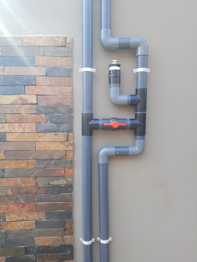 Neatly plumbed PVC piping and valves connecting solar panels to the pool system