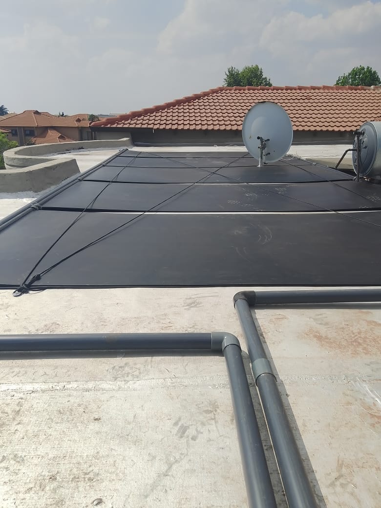 Solar pool heating panels installed on a roof, plumbed into the pool system