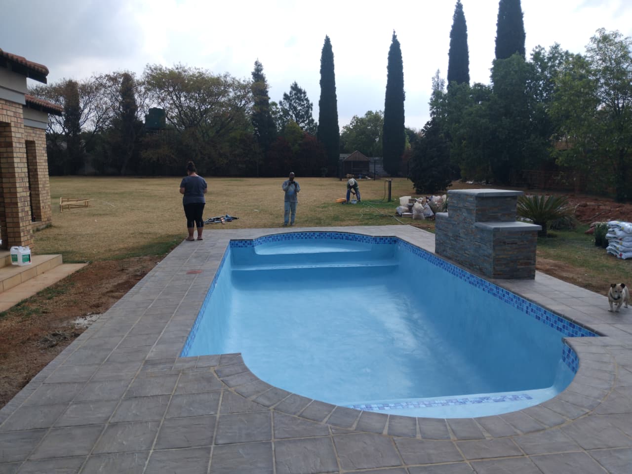 Newly built pool finished with mosaic waterline tiles and paved surround